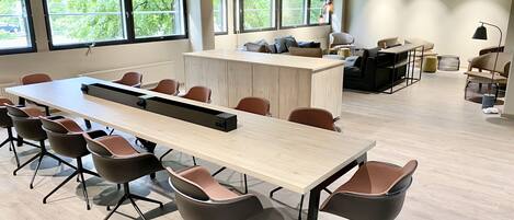 A modern meeting room with a long table, multiple chairs, and a central island.