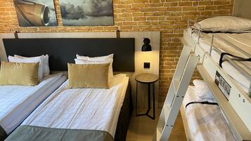 A hotel room with two beds, a small table, and a bunk bed.