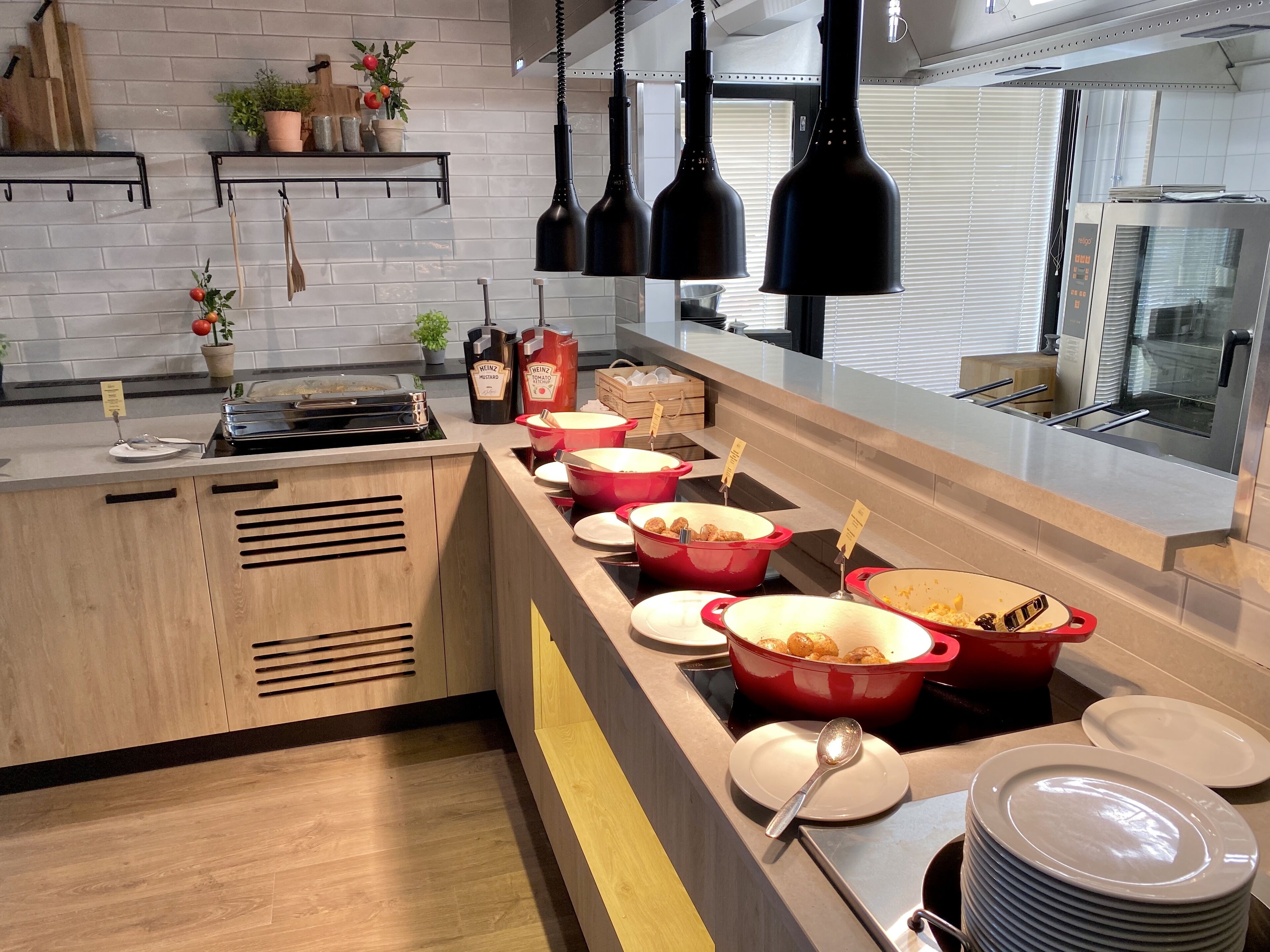 Une cuisine moderne avec un espace buffet, comprenant des casseroles rouges et une variété de plats.