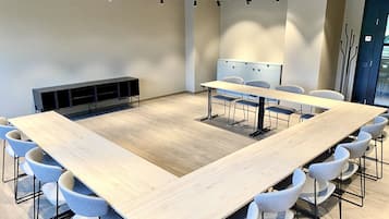 Una sala conferenze con un ampio tavolo rettangolare, diverse sedie, una lavagna e un armadietto a parete.