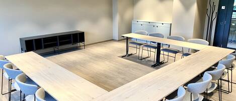 A conference room with a large rectangular table, multiple chairs, a whiteboard, and a storage unit against the wall.