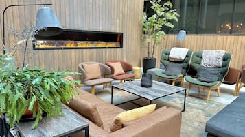Un salón moderno con chimenea, asientos cómodos y un ventanal grande.