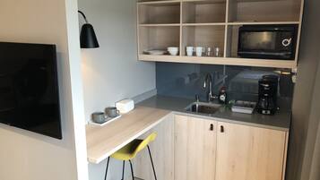 Una cocina compacta con microondas, fregadero y taburetes de bar.