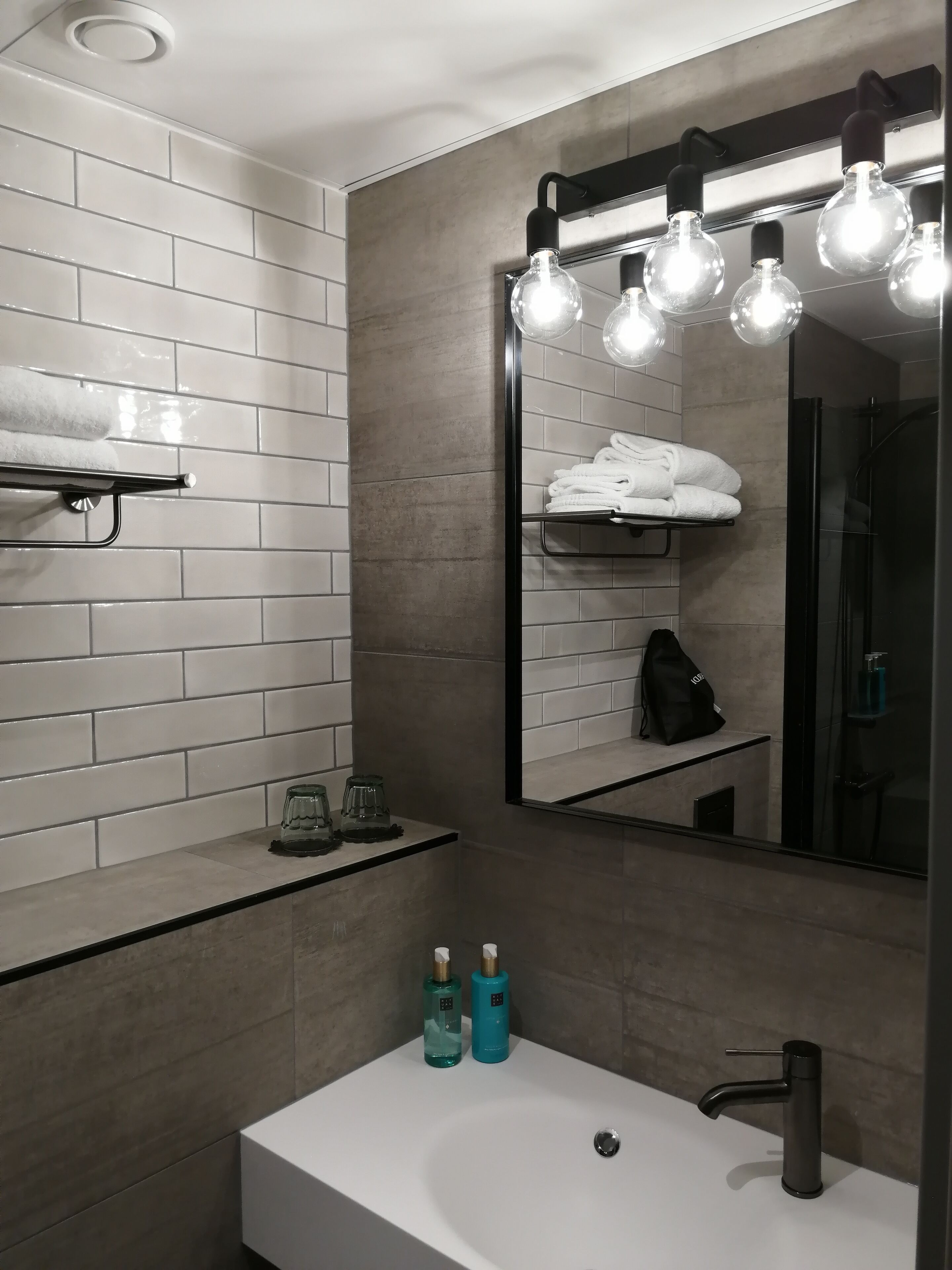 A modern bathroom with a white sink, a mirror, and a towel rack.