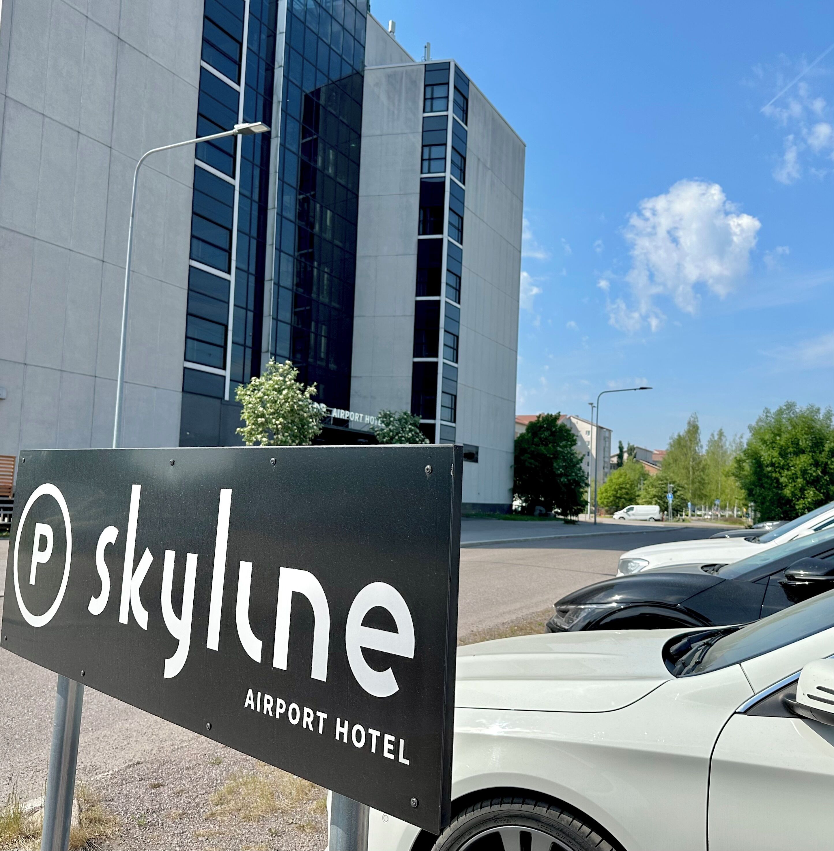 A sign for the Skyline Airport Hotel with a modern building in the background.