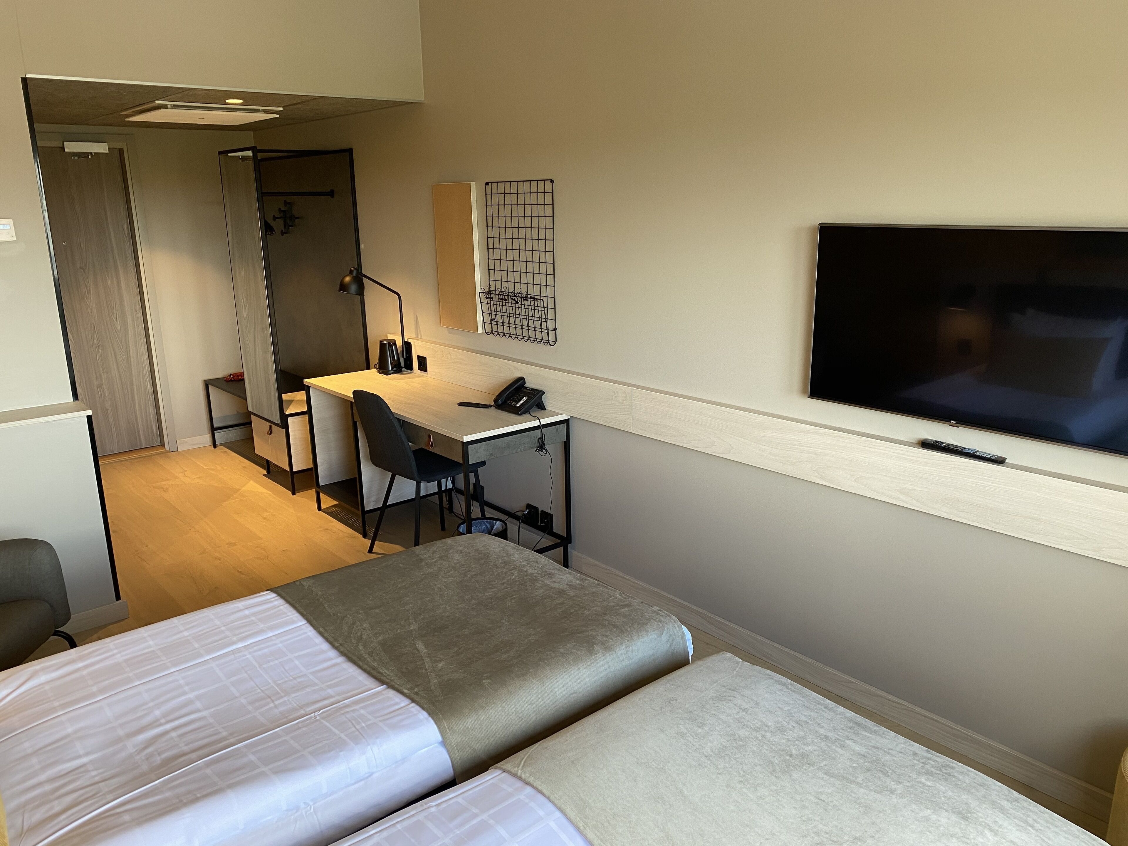 Ett hotellrum med en säng, ett skrivbord, en stol, en tv och en garderob.