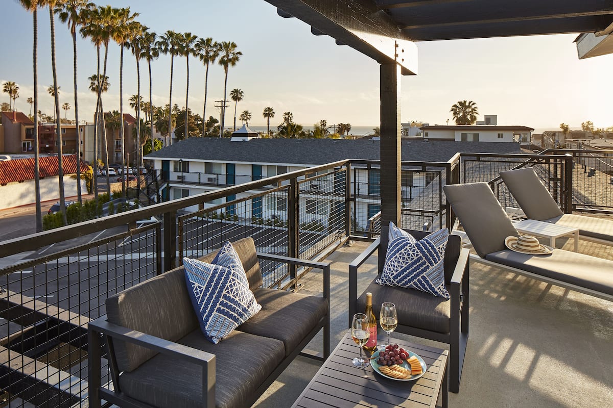 A rooftop patio with outdoor seating, a pool, and a view of palm trees and buildings.