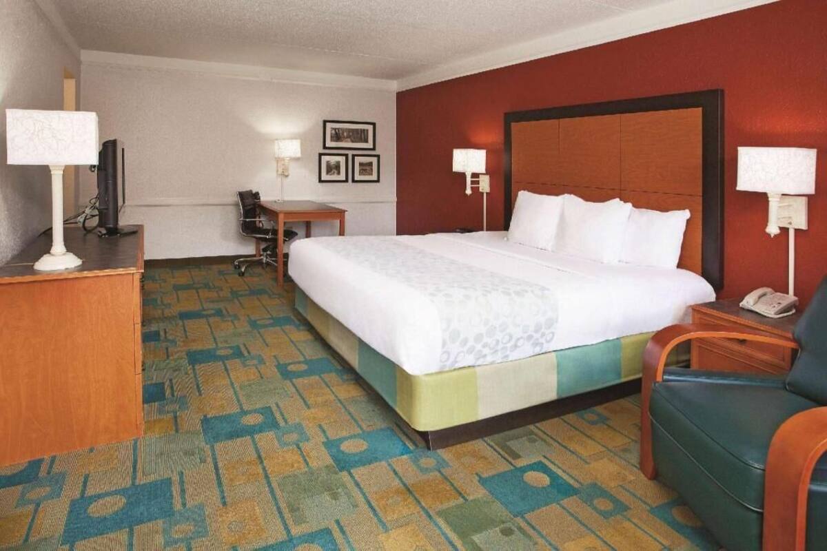 A hotel room with a bed, desk, chair, and a television.