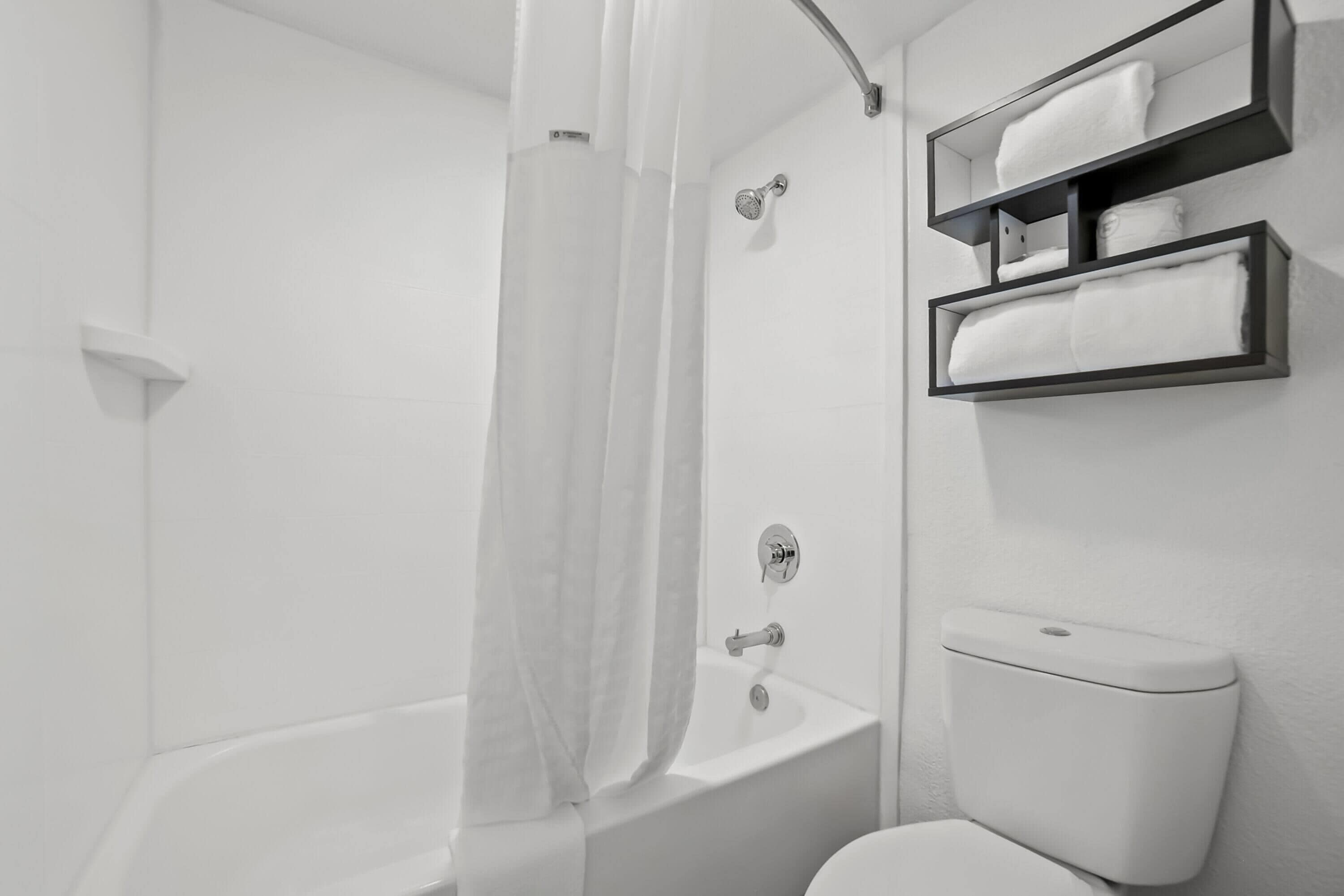 Ein modernes Badezimmer mit Badewanne, Toilette und integrierten Ablagen für Handtücher.