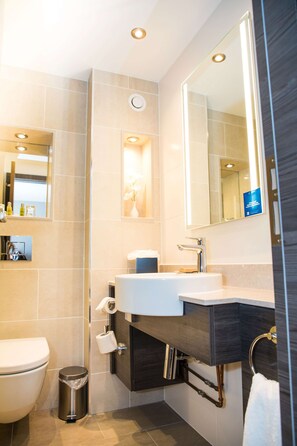 Une salle de bain moderne avec un lavabo blanc, un meuble-lavabo foncé et un grand miroir.