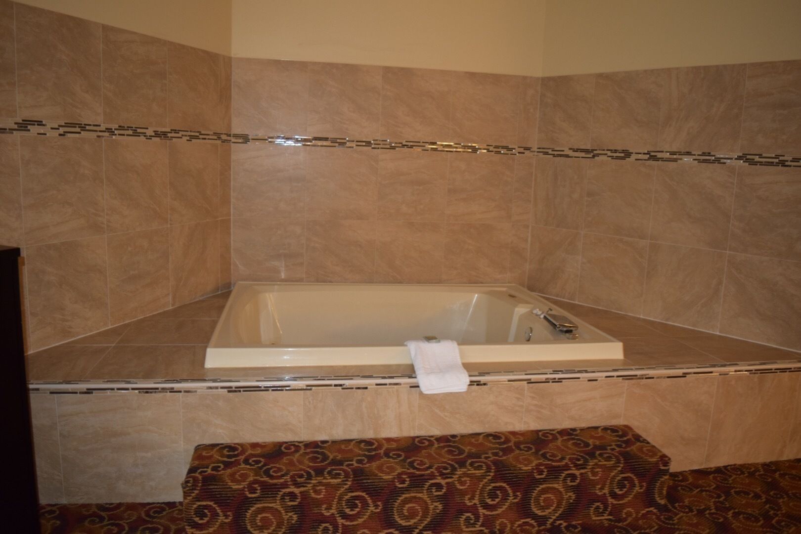 A bathroom with a bathtub, a towel, and patterned carpet.