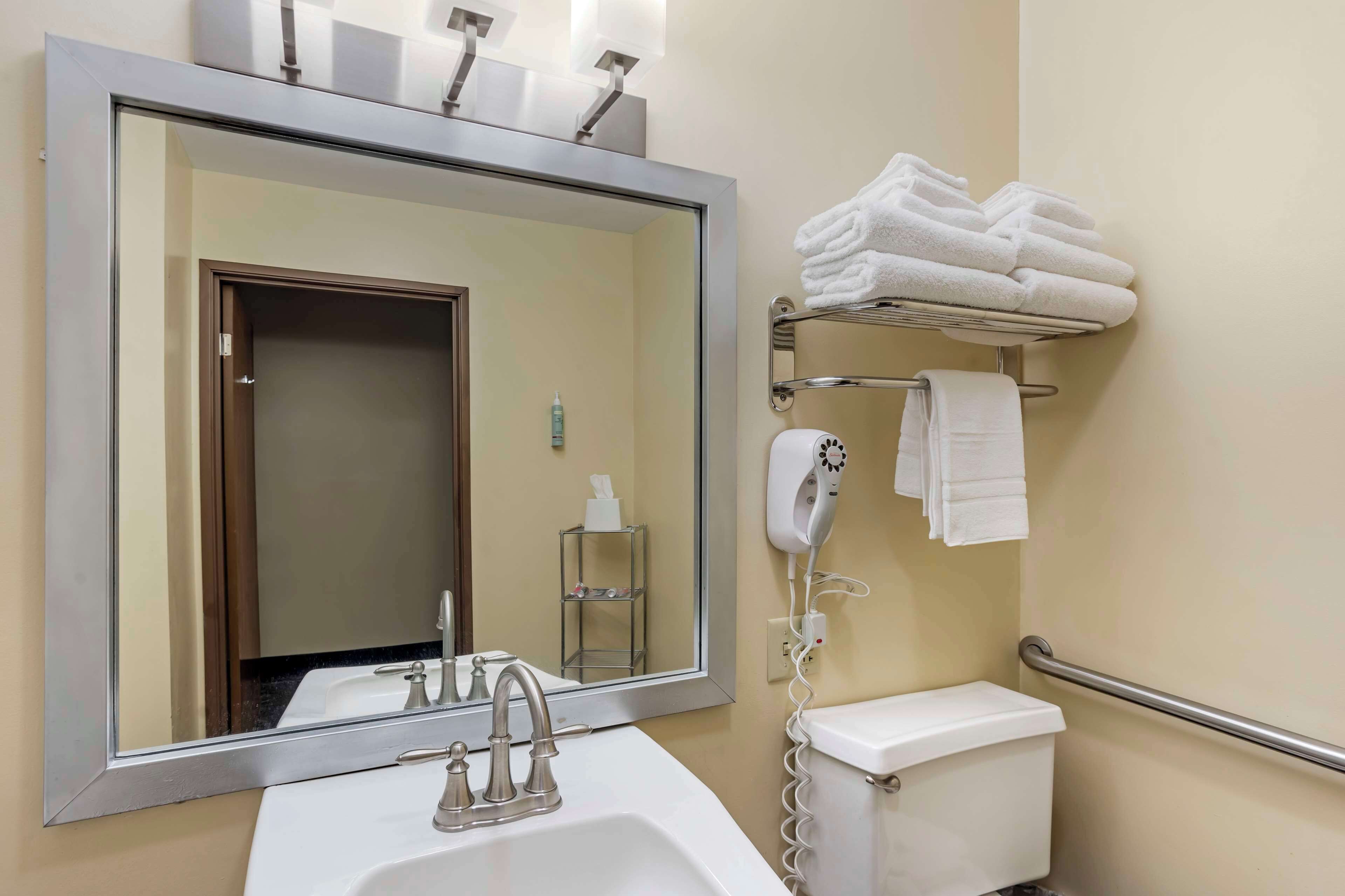 A bathroom with a sink, mirror, towel rack, and a hairdryer.