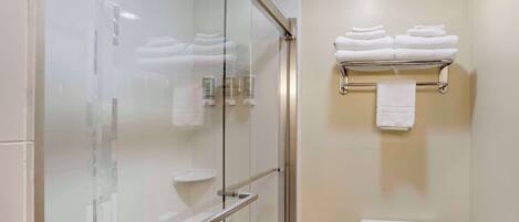 Een moderne badkamer met een douchecabine van glas, een toilet en een handdoekrek met opgevouwen handdoeken.