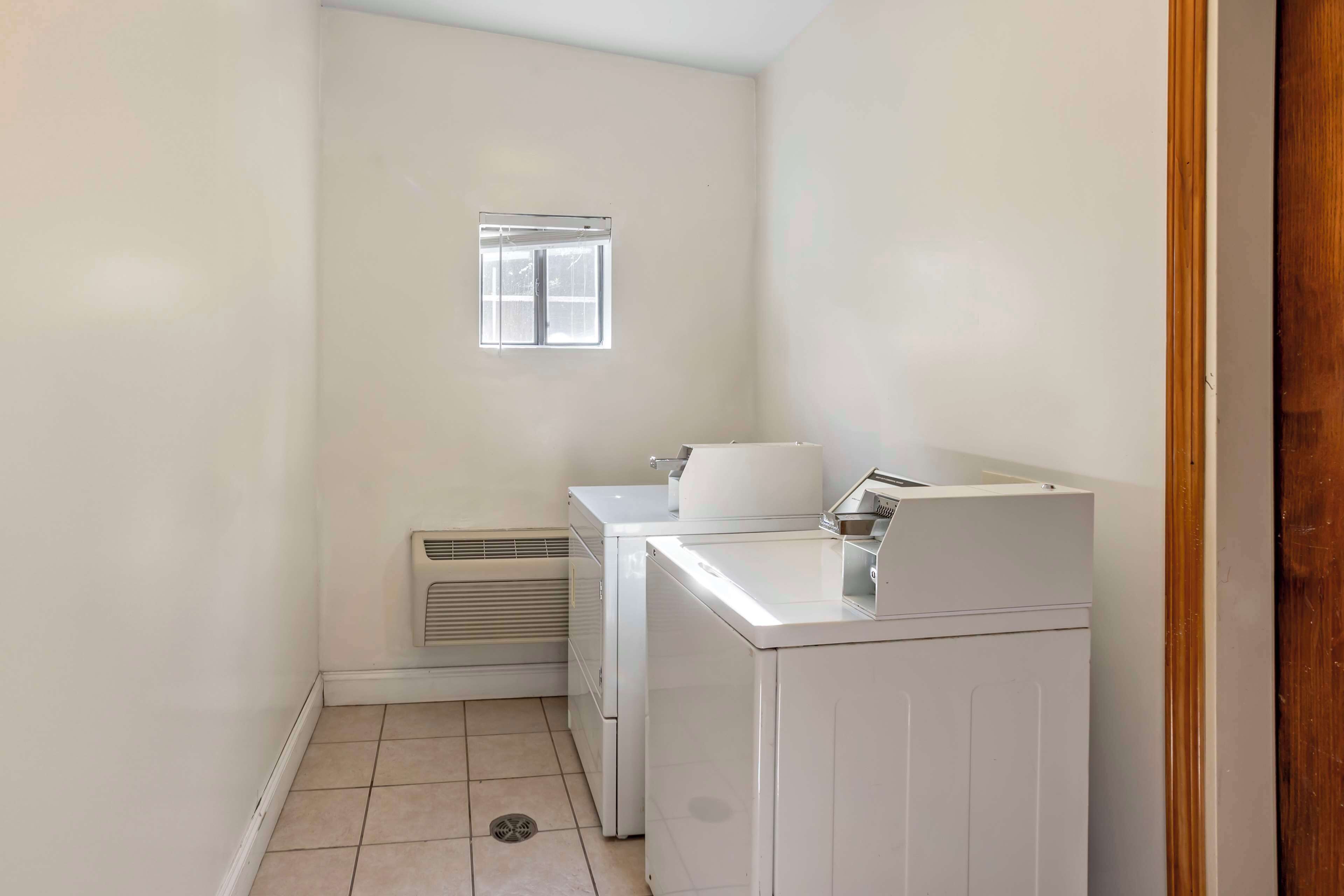 A compact laundry room with a washing machine, dryer, and a small window.