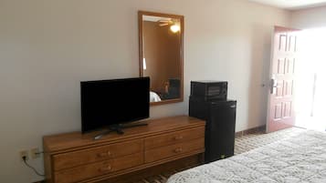Hotelkamer met een houten dressoir, een flatscreen televisie, een magnetron en een bed met een beddekleed met dessin.