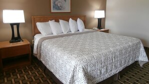 A hotel room with a large bed, two bedside tables, a nightstand, a wall-mounted telephone, and a framed picture above the bed. - Americas Best Value Inn Blue Ridge (Blue Ridge)