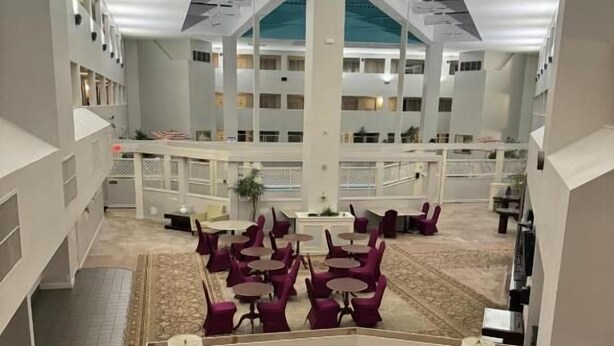 Un vestíbulo de hotel con una zona de estar central, varios pisos a la vista y una alfombra estampada.