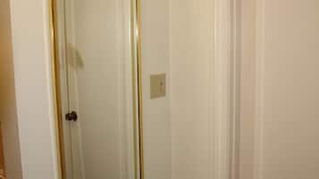 A narrow hallway with a door and a large mirror on the wall.