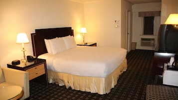 A hotel room with a large bed, two bedside tables with lamps, a chair, and a television.