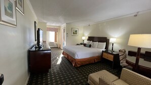 Habitación de hotel con una cama grande, un escritorio con lámpara, una silla y un televisor sobre un aparador.