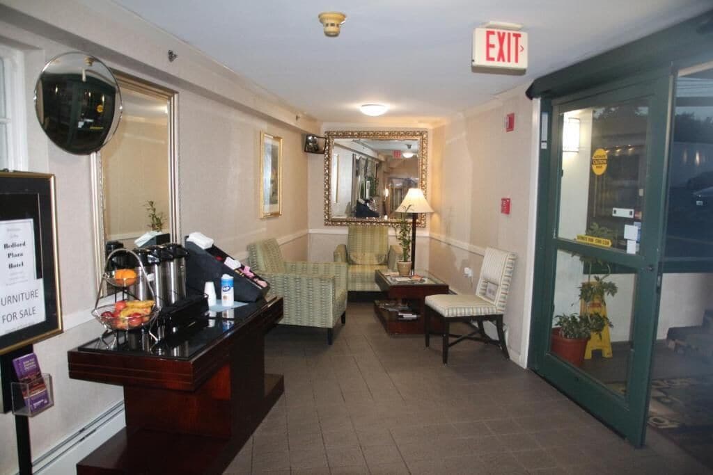 Vestíbulo de hotel con mostrador de recepción, zona de estar y señal de salida.