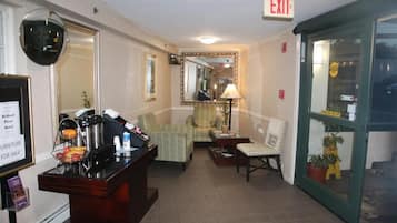 Vestíbulo de hotel con mostrador de recepción, zona de estar y señal de salida.