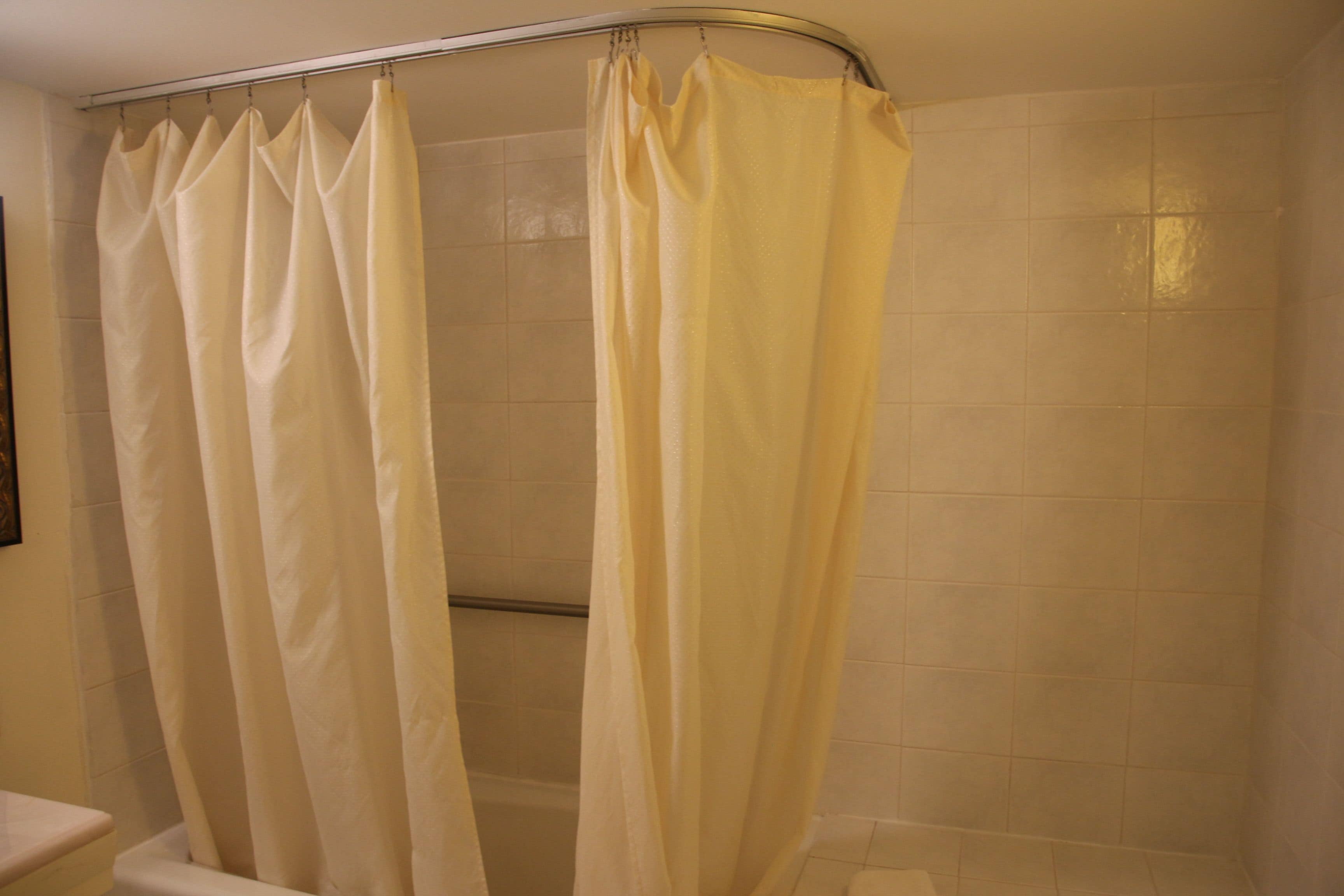 A bathroom with a shower curtain, a toilet, and tiled walls.