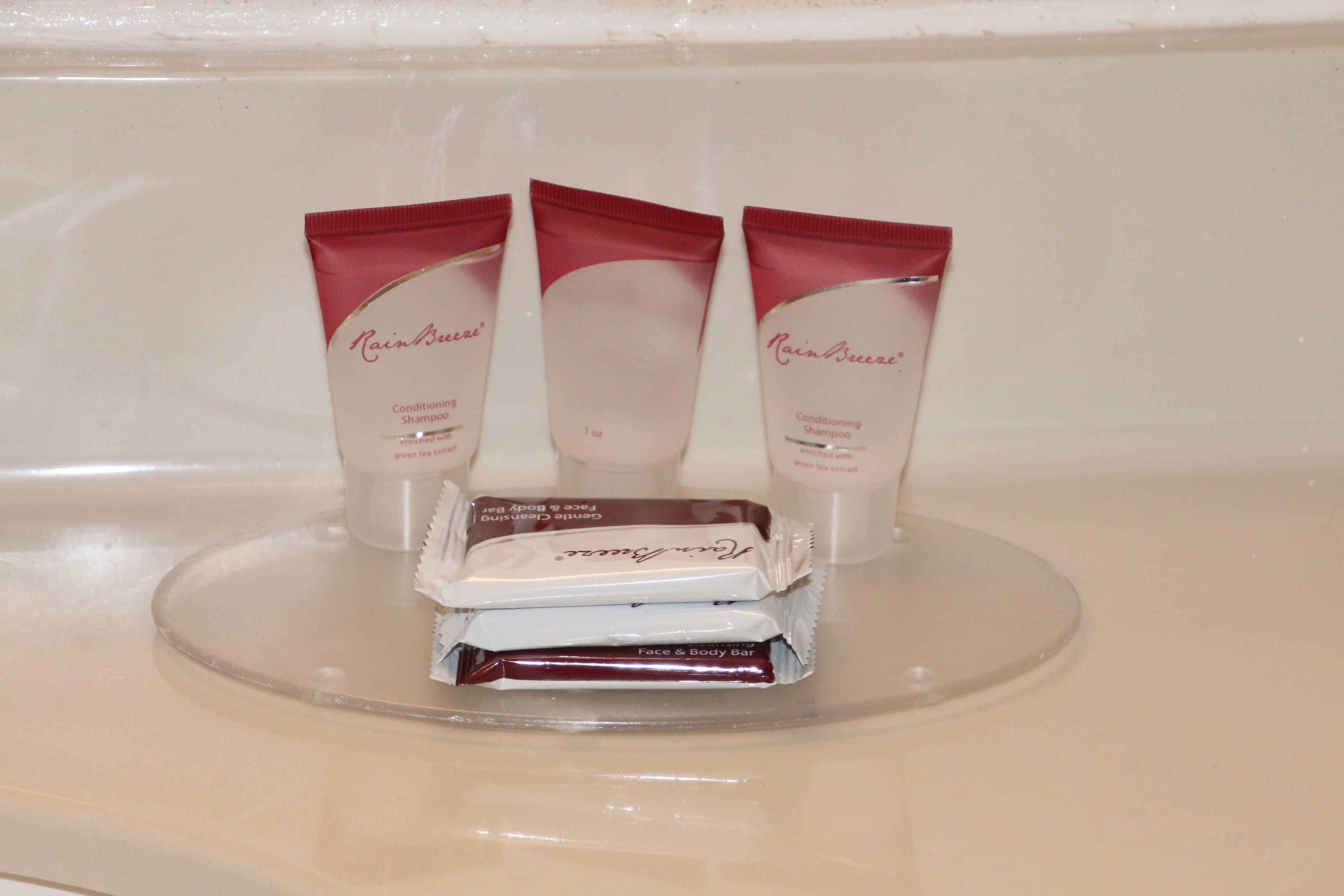 A bathroom counter with three tubes of RainBreeze conditioning shampoo and a bar of RainBreeze face and body bar soap.