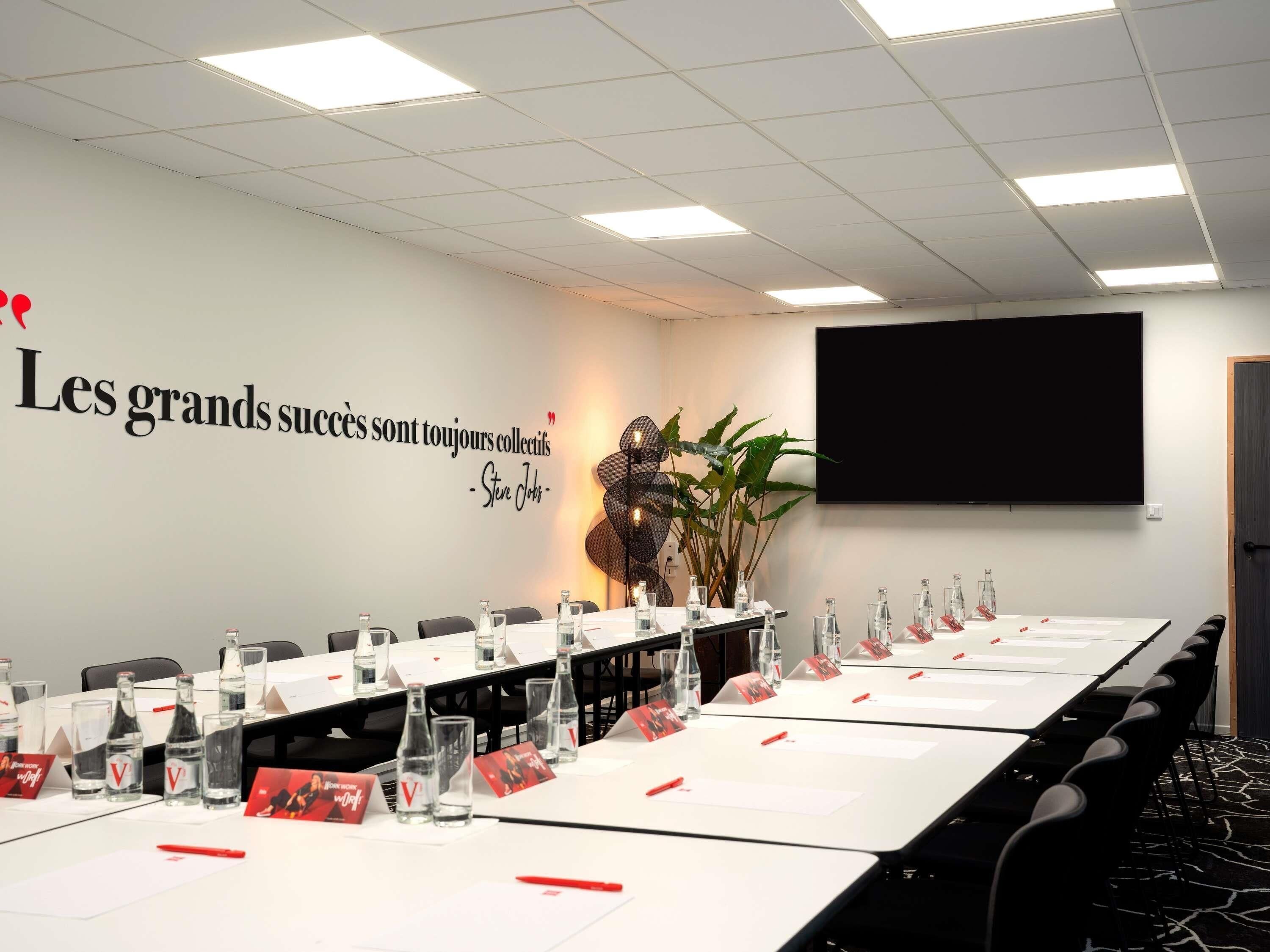 A conference room with a long table, nameplates, water bottles, and a motivational quote on the wall.