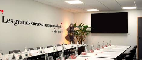 A conference room with a long table, nameplates, water bottles, and a motivational quote on the wall.