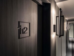 A hallway with a framed number sign, a door, and a wall-mounted light fixture. - ibis Nancy Centre Stanislas (Nancy)
