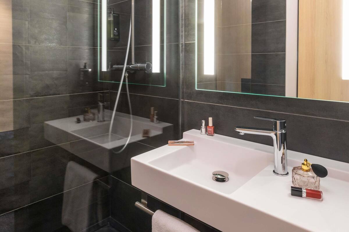 A modern bathroom with two sinks, a glass shower enclosure, and a large mirror.