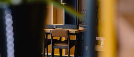 Un comedor con una mesa y sillas de madera, una lámpara colgante y un estante con adornos.