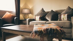 A living room with a sofa, armchairs, a coffee table, and a lamp. - Nevis Bank Inn (Fort William)