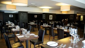 A restaurant with multiple tables set for dining, each with chairs and dining essentials. - Nevis Bank Inn (Fort William)
