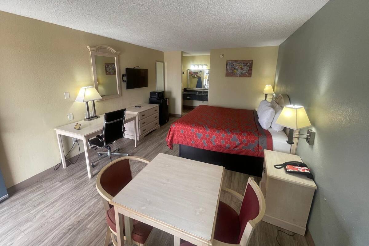 A hotel room with a bed, desk, chair, and a small table.