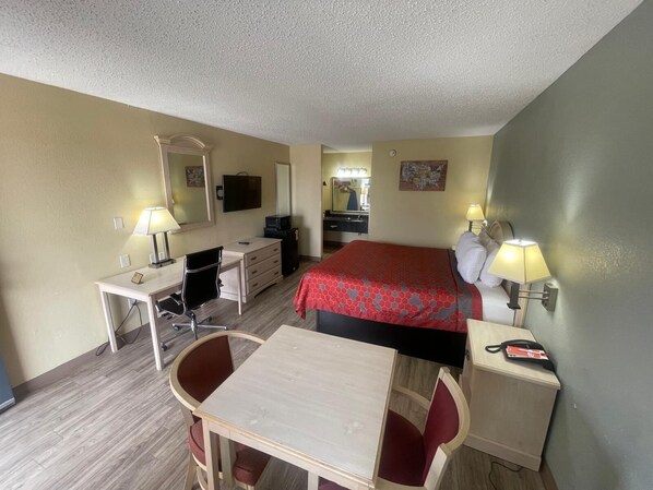A hotel room with a bed, desk, chair, and a small table.