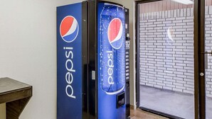 A Pepsi vending machine next to a glass door with a brick wall in the background. - Econo Lodge Falfurrias Hwy 281 (Falfurrias)