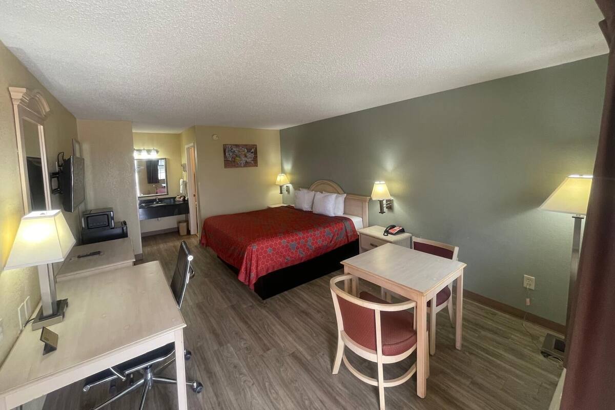 A hotel room with a bed, desk, chair, and a small table.