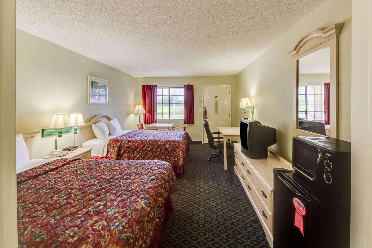 A hotel room with two beds, a desk with a computer, a TV, and a dresser.