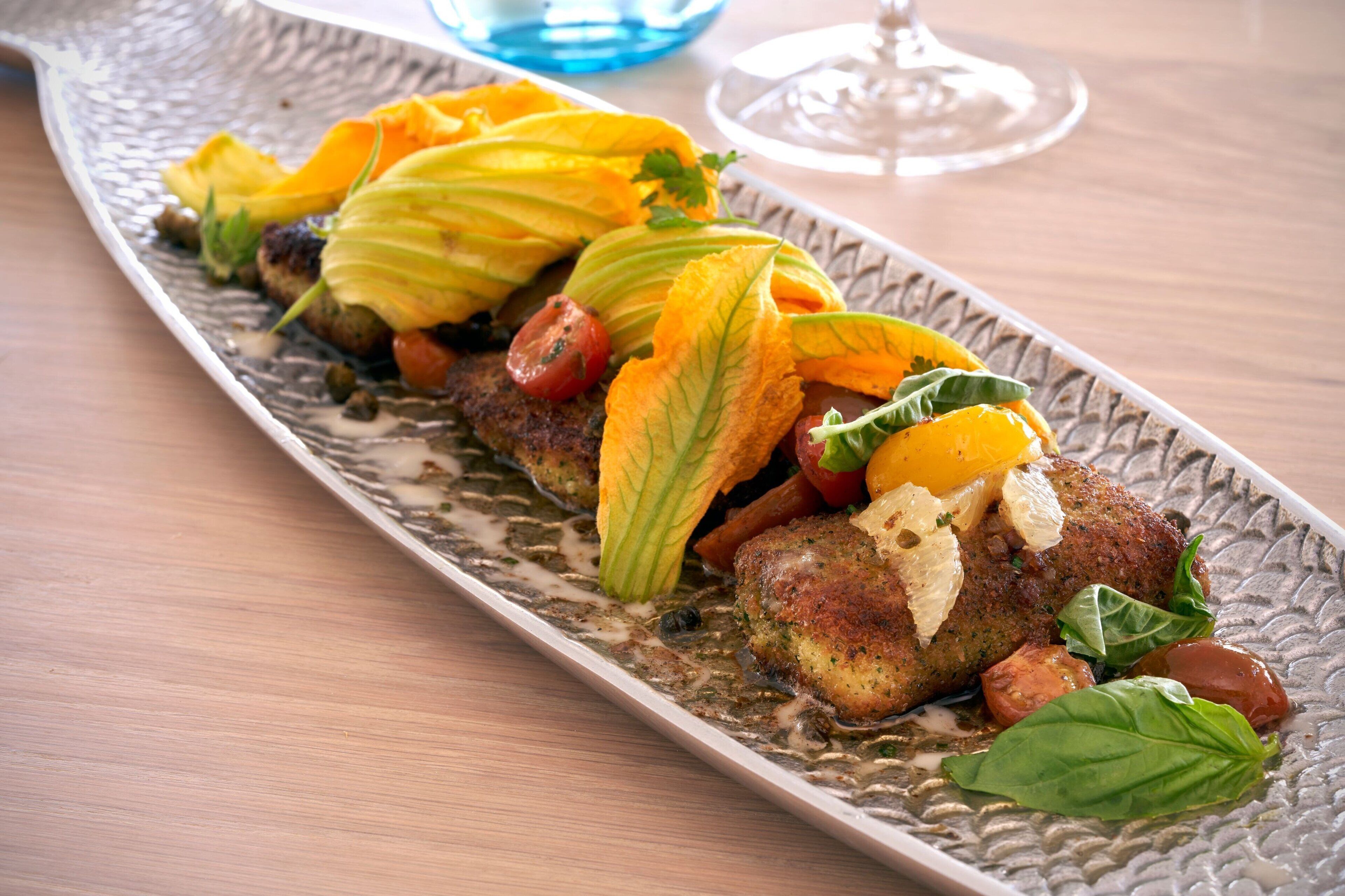Un plato con verduras y carne, adornado con hierbas, sobre un plato con textura.