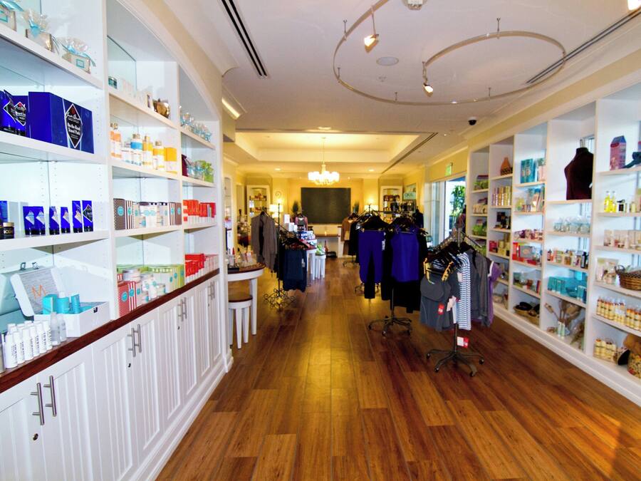 A store with wooden flooring, white shelving, and various products on display.