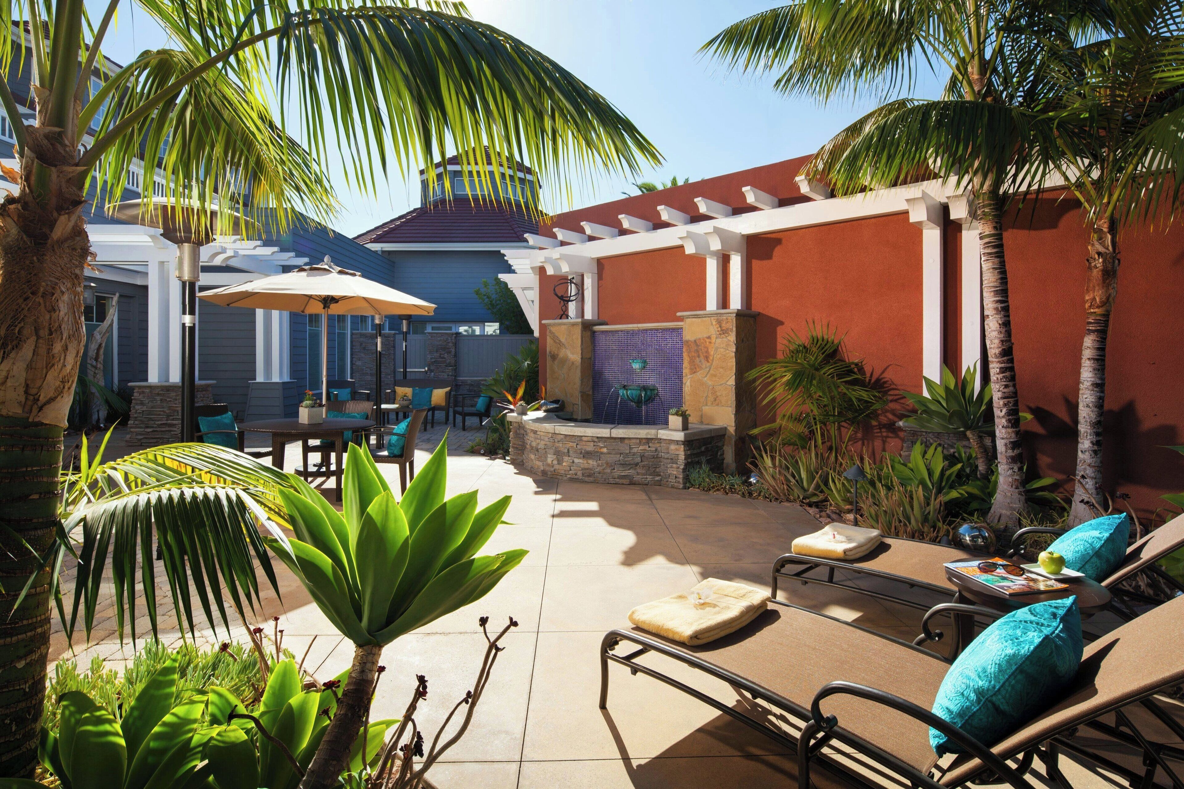 A patio area with lounge chairs, a table, and umbrellas.