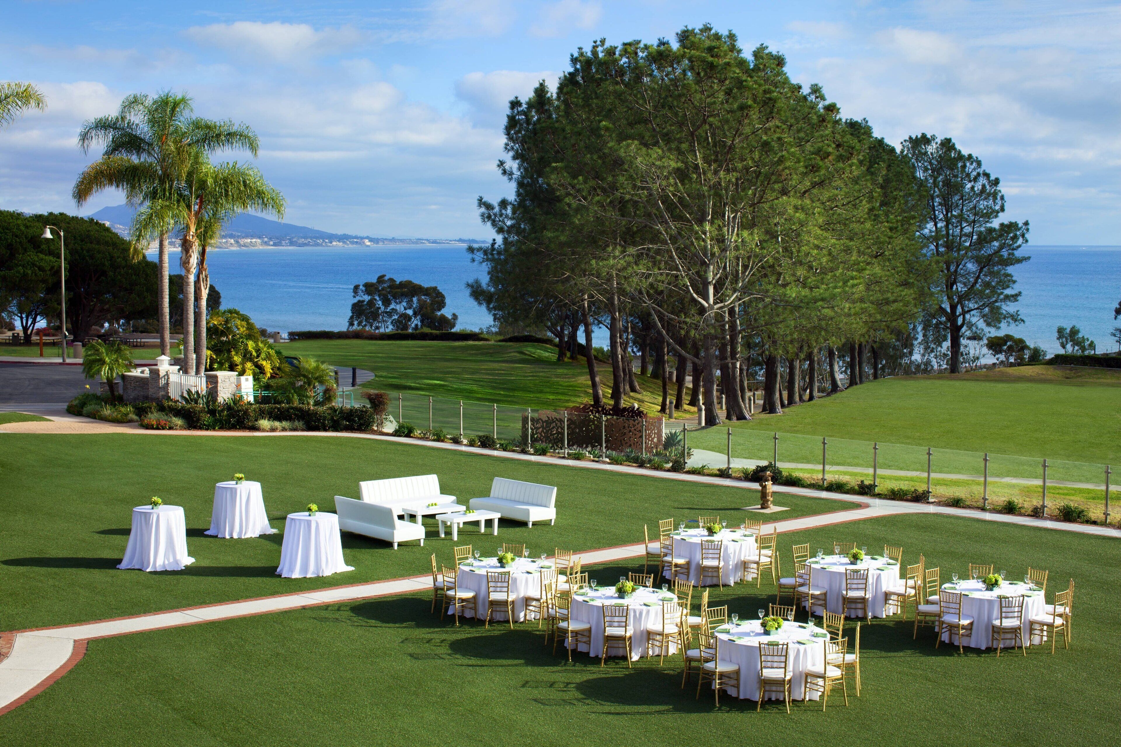Un campo de golf con carpas blancas, mesas y sillas dispuestas para un evento.