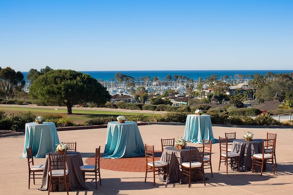 An outdoor patio with tables and chairs, overlooking a coastal town.