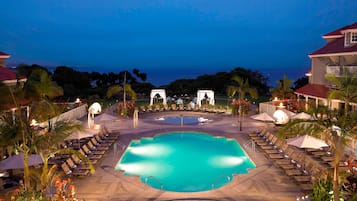 Relax by the resort's central pool surrounded by palm trees and lounge chairs.