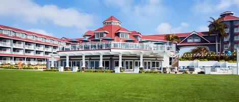 A large hotel with multiple balconies, a central courtyard, and a red-roofed building.