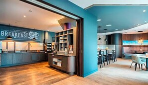 A modern breakfast area with a counter and seating, a visible menu, and a view of the kitchen. - Premier Inn Stuttgart Bad Cannstatt (Stuttgart)