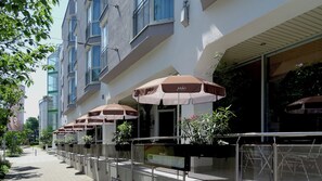 A row of outdoor seating with umbrellas, a building facade, and a pathway. - Premier Inn Stuttgart Bad Cannstatt (Stuttgart)