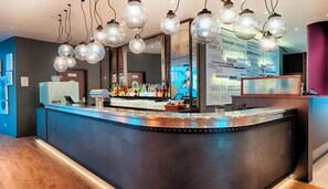 A bar area with a counter, hanging light fixtures, and a digital menu board.